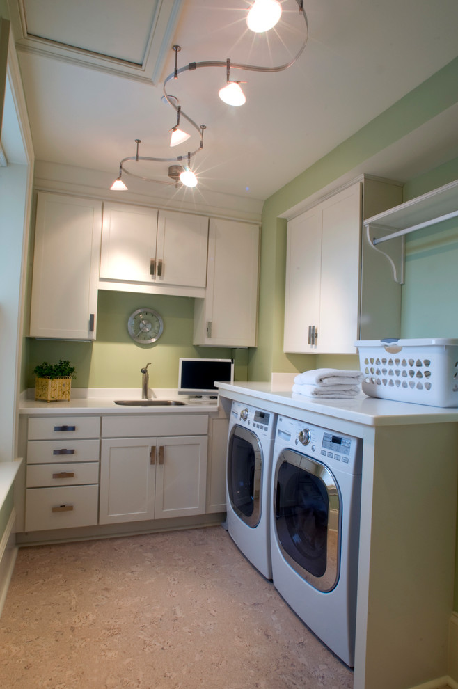 Idéer för att renovera en mellanstor vintage l-formad tvättstuga enbart för tvätt, med en undermonterad diskho, luckor med infälld panel, vita skåp, bänkskiva i kvarts, gröna väggar, korkgolv och en tvättmaskin och torktumlare bredvid varandra