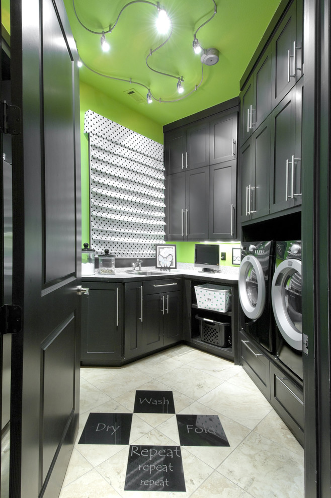 Moderner Hauswirtschaftsraum mit Schrankfronten im Shaker-Stil, schwarzen Schränken, grüner Wandfarbe, Porzellan-Bodenfliesen, Waschmaschine und Trockner nebeneinander und beigem Boden in Sonstige