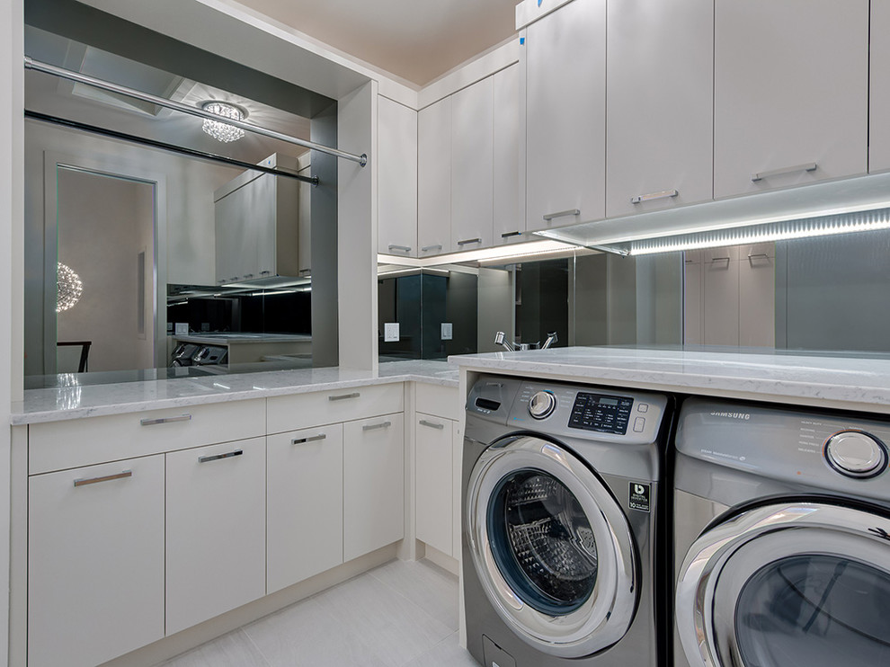 Idéer för funkis l-formade tvättstugor enbart för tvätt, med en undermonterad diskho, släta luckor, vita skåp och en tvättmaskin och torktumlare bredvid varandra