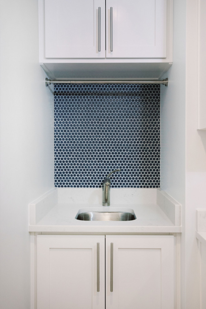 Foto på en vintage vita tvättstuga, med en undermonterad diskho, luckor med infälld panel, vita skåp, blått stänkskydd, stänkskydd i mosaik och vita väggar