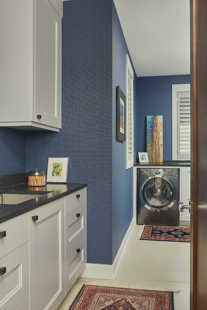 Exempel på ett stort klassiskt grovkök, med en undermonterad diskho, luckor med infälld panel, vita skåp, granitbänkskiva, blå väggar, klinkergolv i keramik och en tvättmaskin och torktumlare bredvid varandra