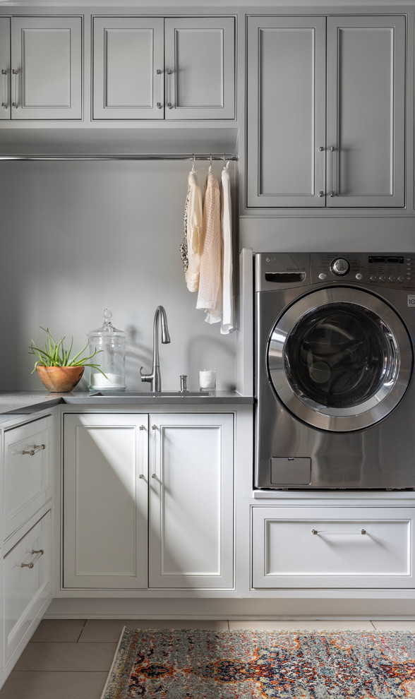 Bild på en vintage grå grått tvättstuga, med en undermonterad diskho, luckor med infälld panel, grå väggar, en tvättmaskin och torktumlare bredvid varandra och beiget golv