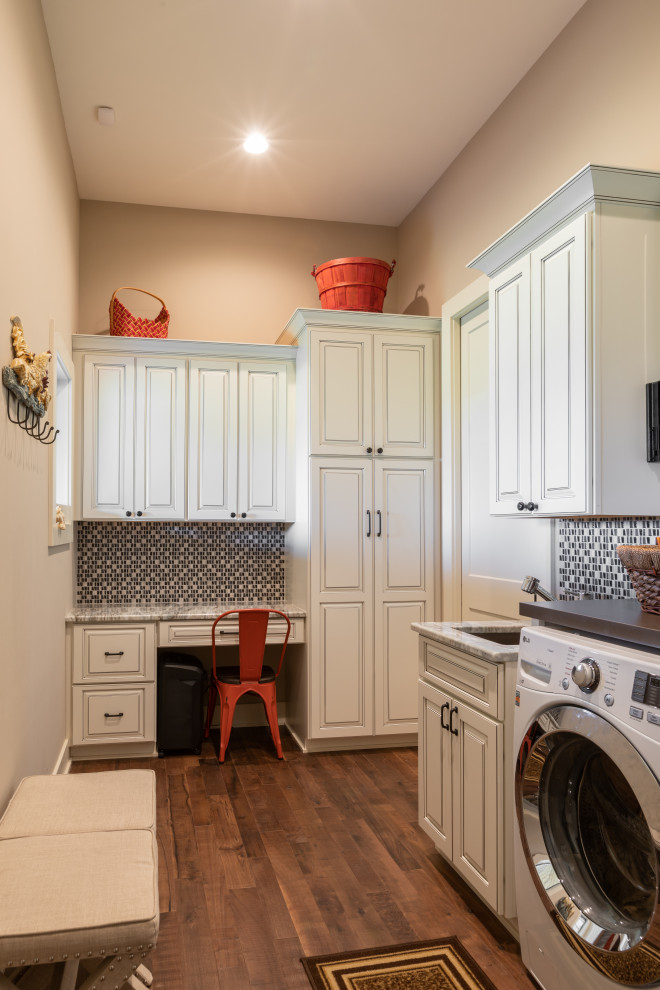 Example of a large mountain style l-shaped dark wood floor and brown floor dedicated laundry room design in Omaha with an undermount sink, raised-panel cabinets, white cabinets, granite countertops, beige walls, a side-by-side washer/dryer and gray countertops