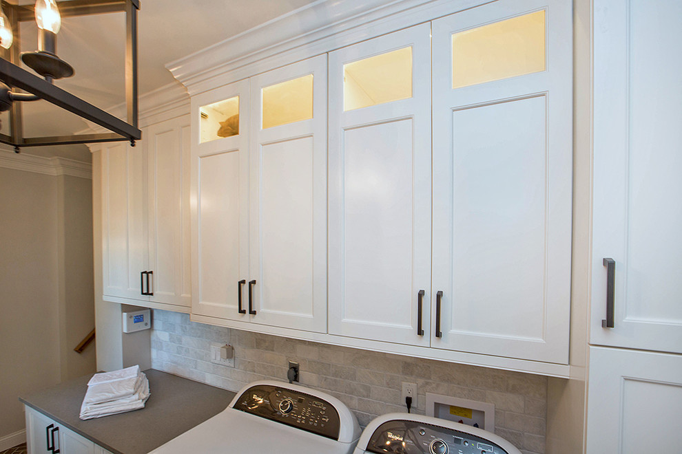 Esempio di una sala lavanderia shabby-chic style di medie dimensioni con ante in stile shaker, ante bianche, top in quarzo composito, pareti grigie, pavimento in gres porcellanato, lavatrice e asciugatrice affiancate e pavimento marrone