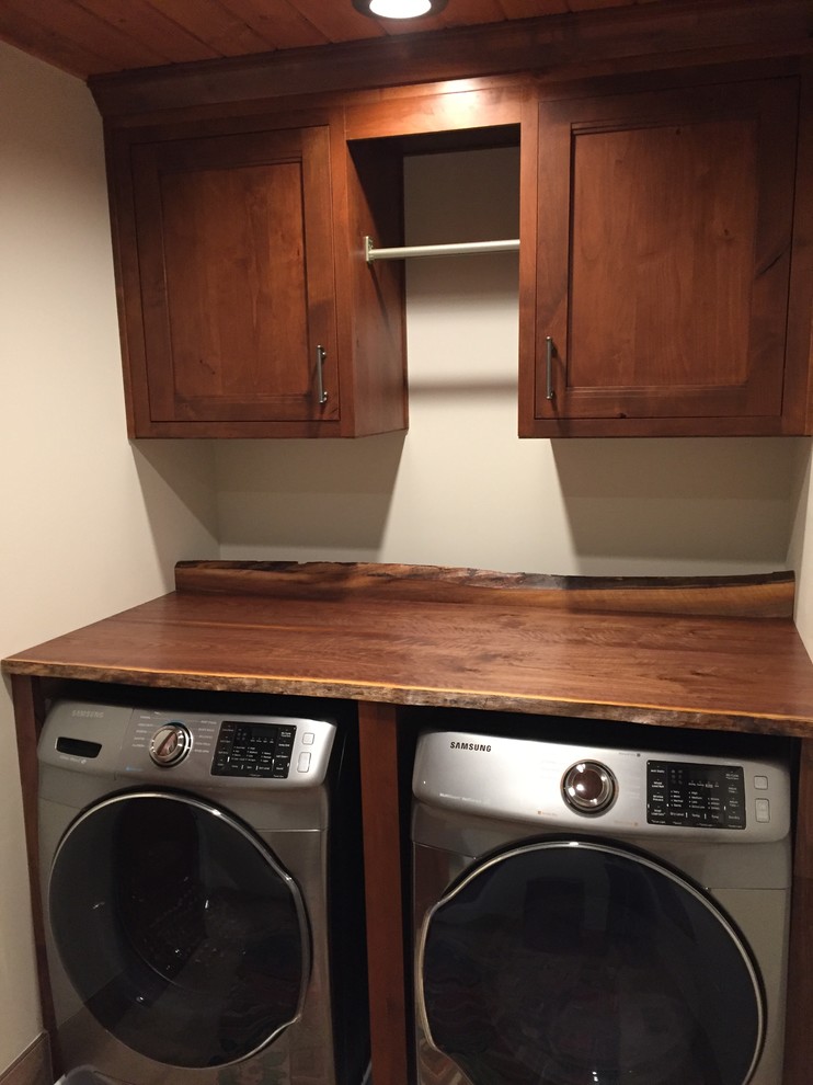 Small mountain style single-wall porcelain tile dedicated laundry room photo in Baltimore with beaded inset cabinets, medium tone wood cabinets, wood countertops and a side-by-side washer/dryer