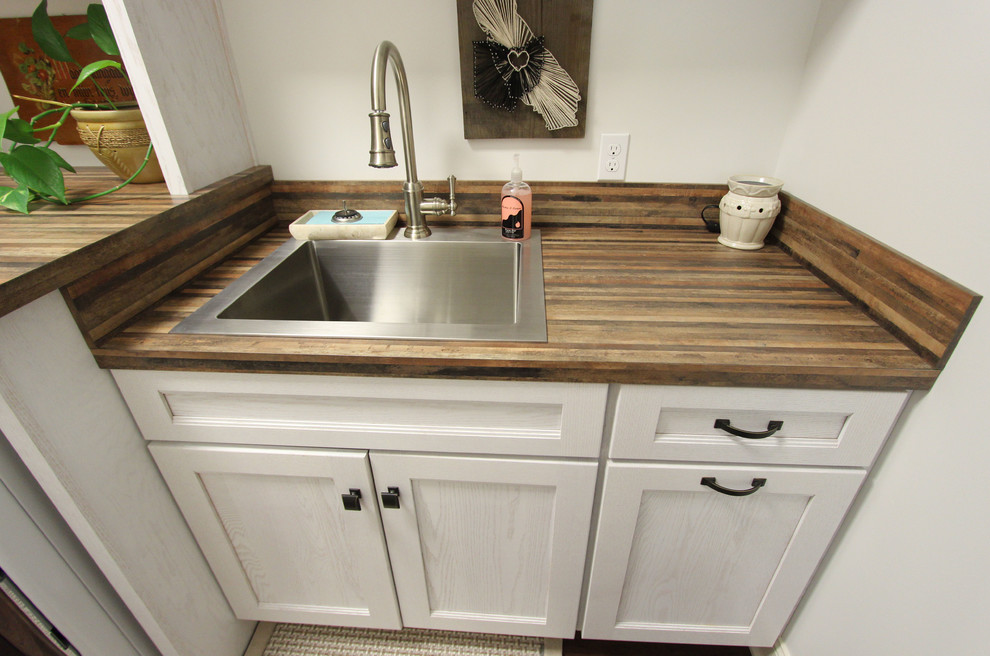 Mid-sized mountain style single-wall dark wood floor and brown floor dedicated laundry room photo in Cleveland with a drop-in sink, recessed-panel cabinets, white cabinets, laminate countertops and a side-by-side washer/dryer