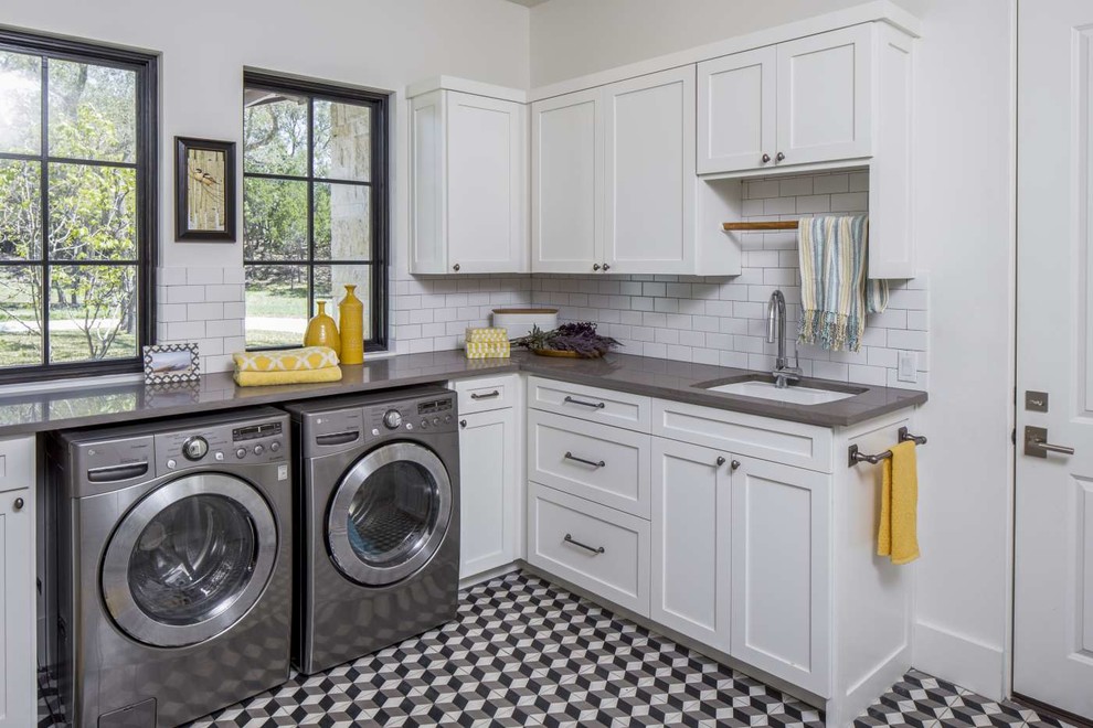 Inspiration för en stor vintage grå l-formad grått tvättstuga enbart för tvätt, med en undermonterad diskho, skåp i shakerstil, vita skåp, bänkskiva i kvarts, vita väggar, en tvättmaskin och torktumlare bredvid varandra, flerfärgat golv och klinkergolv i keramik