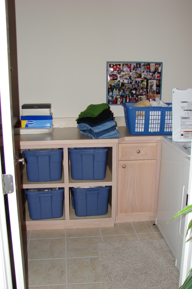 Immagine di una piccola sala lavanderia classica con ante lisce, ante in legno chiaro, top in laminato, pareti beige, lavatrice e asciugatrice affiancate e pavimento con piastrelle in ceramica