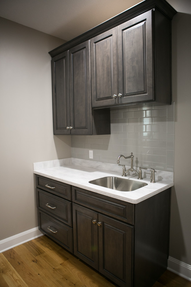 Small transitional galley medium tone wood floor and brown floor dedicated laundry room photo in Indianapolis with an undermount sink, raised-panel cabinets, dark wood cabinets, gray walls, a side-by-side washer/dryer and white countertops