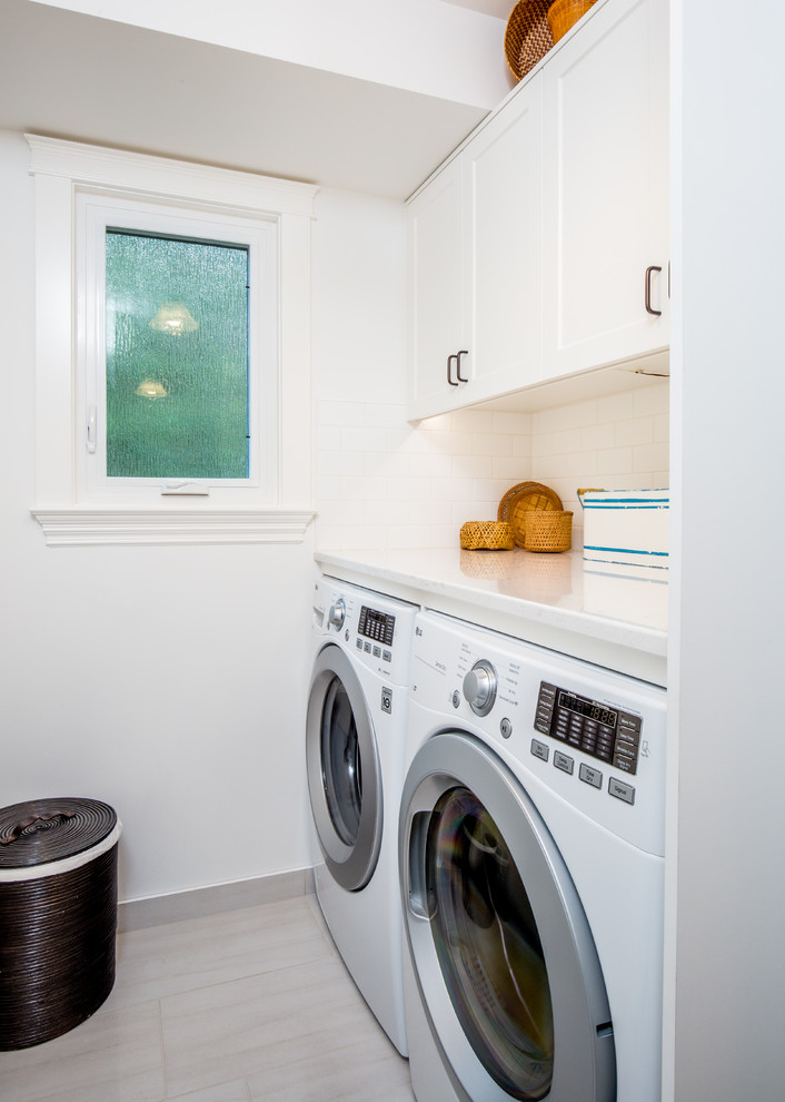 This is an example of a small coastal single-wall utility room in Vancouver with shaker cabinets, white cabinets, quartz worktops, white walls, ceramic flooring and a side by side washer and dryer.