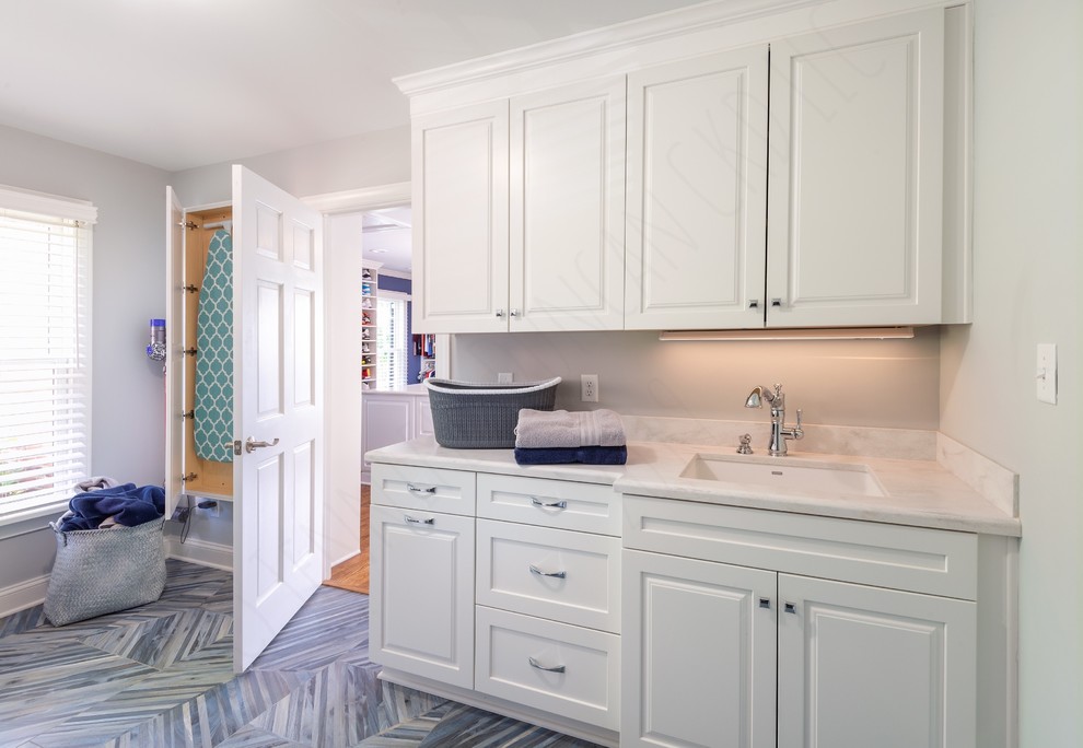 Idéer för en stor klassisk grå parallell tvättstuga enbart för tvätt, med en undermonterad diskho, luckor med infälld panel, vita skåp, bänkskiva i koppar, grå väggar, klinkergolv i porslin, en tvättmaskin och torktumlare bredvid varandra och blått golv