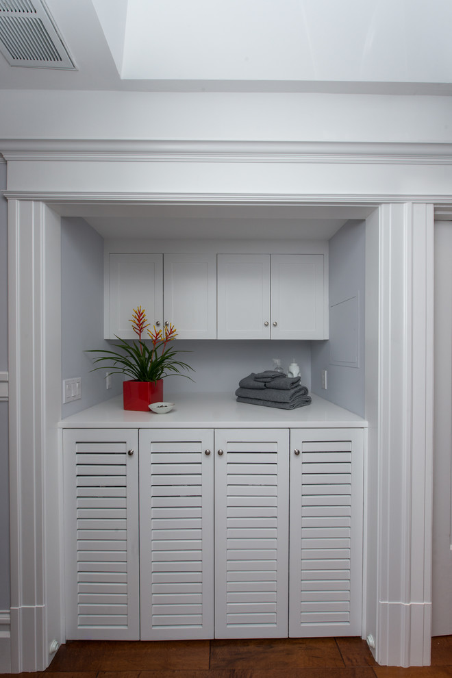 Photo of a medium sized classic single-wall laundry cupboard in San Francisco with louvered cabinets, white cabinets, blue walls, a side by side washer and dryer, grey floors and white worktops.