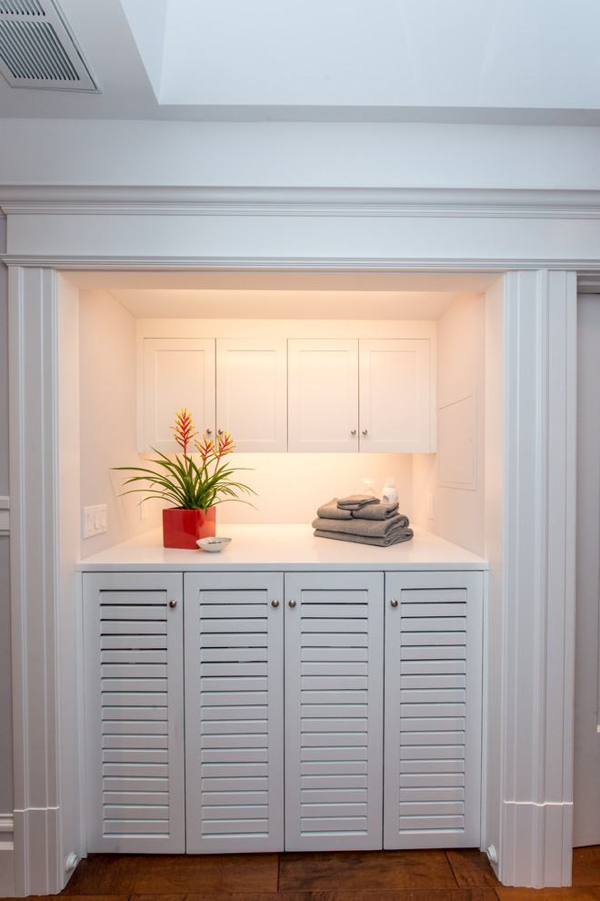 Design ideas for a medium sized traditional single-wall laundry cupboard in San Francisco with louvered cabinets, white cabinets, blue walls, a side by side washer and dryer, grey floors and white worktops.