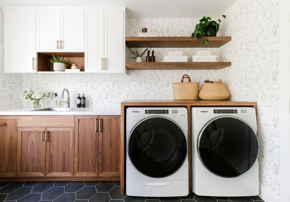 This is an example of a medium sized classic galley separated utility room in San Francisco with a built-in sink, shaker cabinets, medium wood cabinets, engineered stone countertops, white walls, porcelain flooring, a side by side washer and dryer, black floors, white worktops and wallpapered walls.