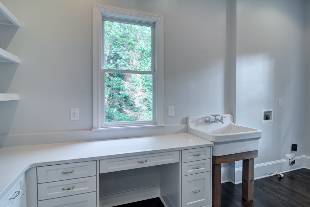 Inspiration for a large traditional l-shaped utility room in Atlanta with a belfast sink, recessed-panel cabinets, white cabinets, white walls, dark hardwood flooring and a side by side washer and dryer.