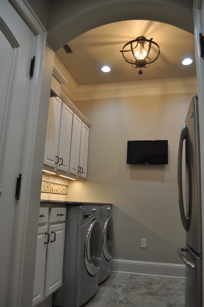 Exempel på en mellanstor medelhavsstil parallell tvättstuga enbart för tvätt, med luckor med upphöjd panel, vita skåp, granitbänkskiva, beige väggar, klinkergolv i keramik och en tvättmaskin och torktumlare bredvid varandra
