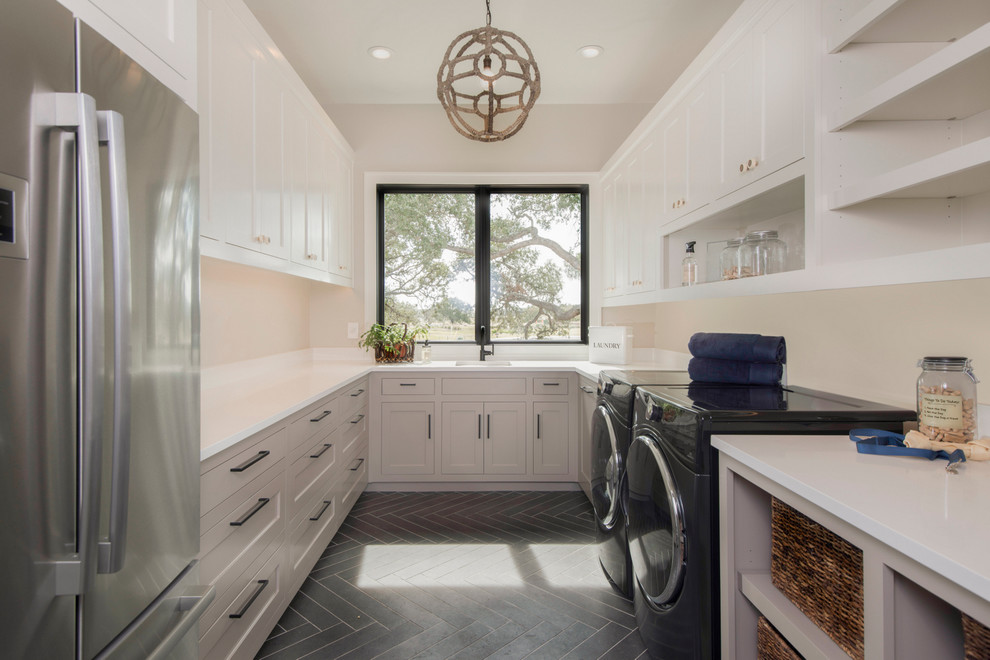 Immagine di una lavanderia tradizionale con lavello sottopiano, ante in stile shaker, ante bianche, pareti beige e pavimento nero