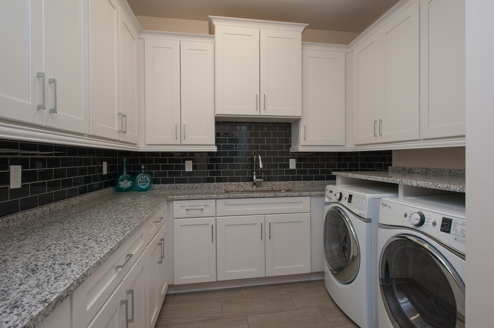 Immagine di una grande sala lavanderia tradizionale con lavello da incasso, ante lisce, ante bianche, lavatrice e asciugatrice affiancate e pareti beige