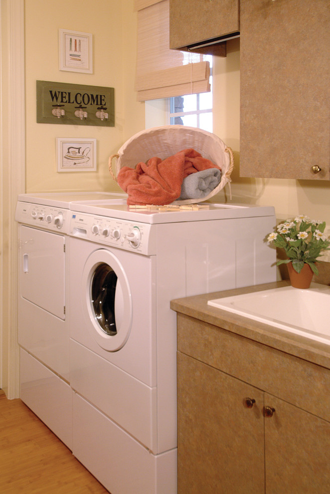 Bild på en stor lantlig parallell tvättstuga enbart för tvätt, med en nedsänkt diskho, släta luckor, bruna skåp, bänkskiva i koppar, mellanmörkt trägolv, en tvättmaskin och torktumlare bredvid varandra och beige väggar