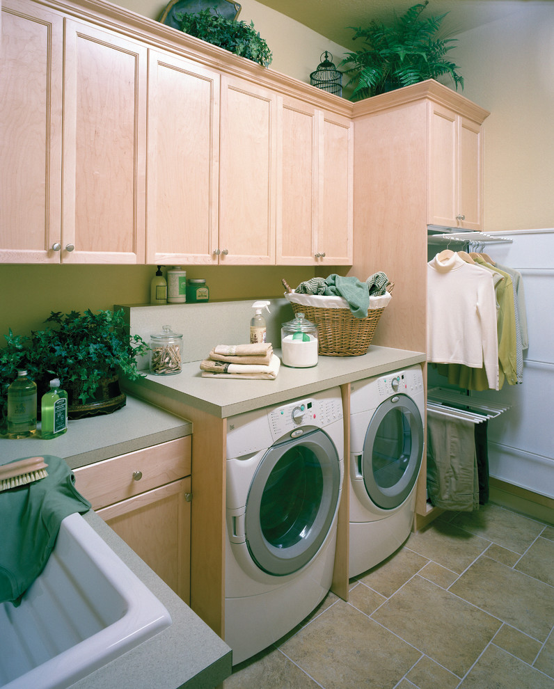 Medelhavsstil inredning av en stor parallell tvättstuga enbart för tvätt, med en nedsänkt diskho, luckor med infälld panel, skåp i ljust trä, laminatbänkskiva, travertin golv, en tvättmaskin och torktumlare bredvid varandra och beige väggar