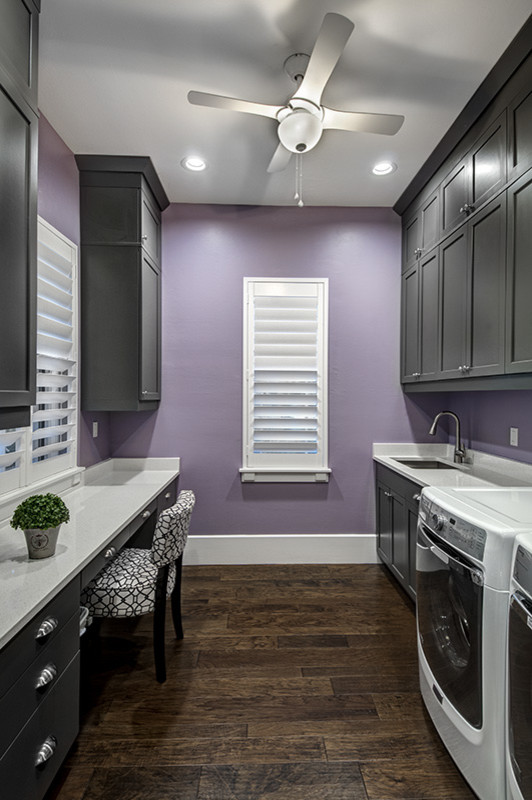 Photo of a large traditional galley utility room in Miami with a submerged sink, recessed-panel cabinets, grey cabinets, quartz worktops, purple walls, dark hardwood flooring and a side by side washer and dryer.