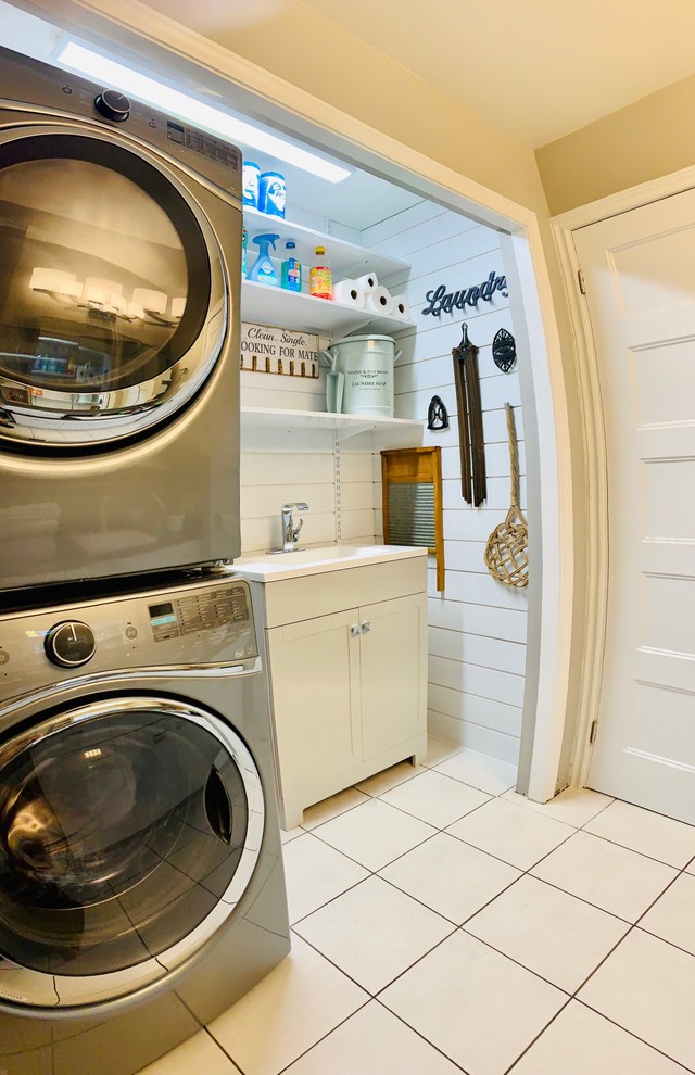 Idée de décoration pour une petite buanderie linéaire nordique avec un placard, un évier intégré, un placard à porte shaker, des portes de placard grises, un plan de travail en quartz modifié, un mur blanc, un sol en carrelage de céramique, des machines superposées, un sol blanc et un plan de travail blanc.