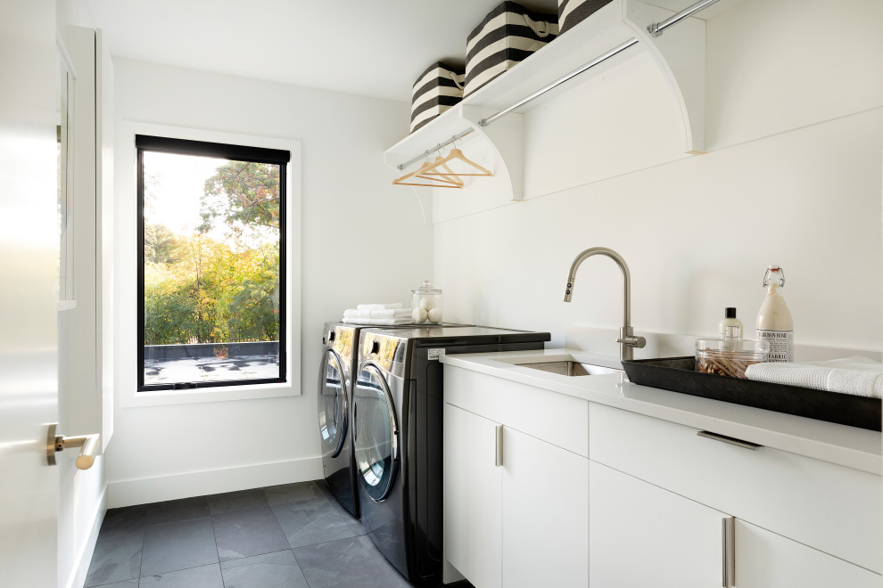 Inspiration for a contemporary single-wall black floor dedicated laundry room remodel in Minneapolis with an undermount sink, flat-panel cabinets, white cabinets, a side-by-side washer/dryer and white countertops