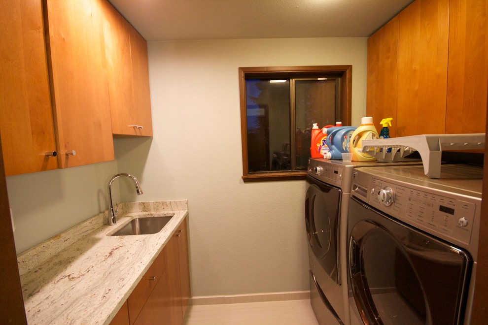 Example of a small minimalist galley ceramic tile utility room design in Seattle with an undermount sink, flat-panel cabinets, medium tone wood cabinets, granite countertops, gray walls and a side-by-side washer/dryer