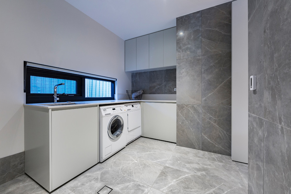 Foto di una lavanderia design con pareti bianche e lavatrice e asciugatrice affiancate