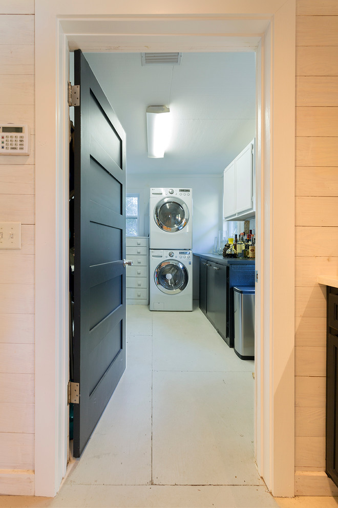 Foto di una sala lavanderia costiera di medie dimensioni con pareti bianche, pavimento in legno verniciato e lavatrice e asciugatrice a colonna