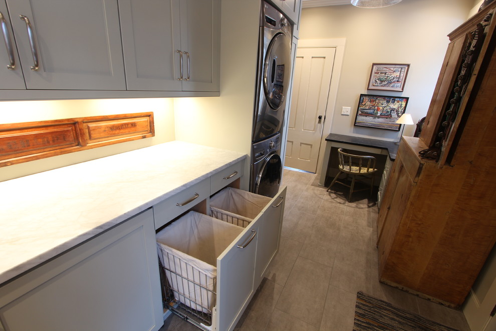 This is an example of a medium sized farmhouse galley utility room in Other with a belfast sink, recessed-panel cabinets, green cabinets, granite worktops, beige walls, porcelain flooring, a stacked washer and dryer, brown floors and green worktops.