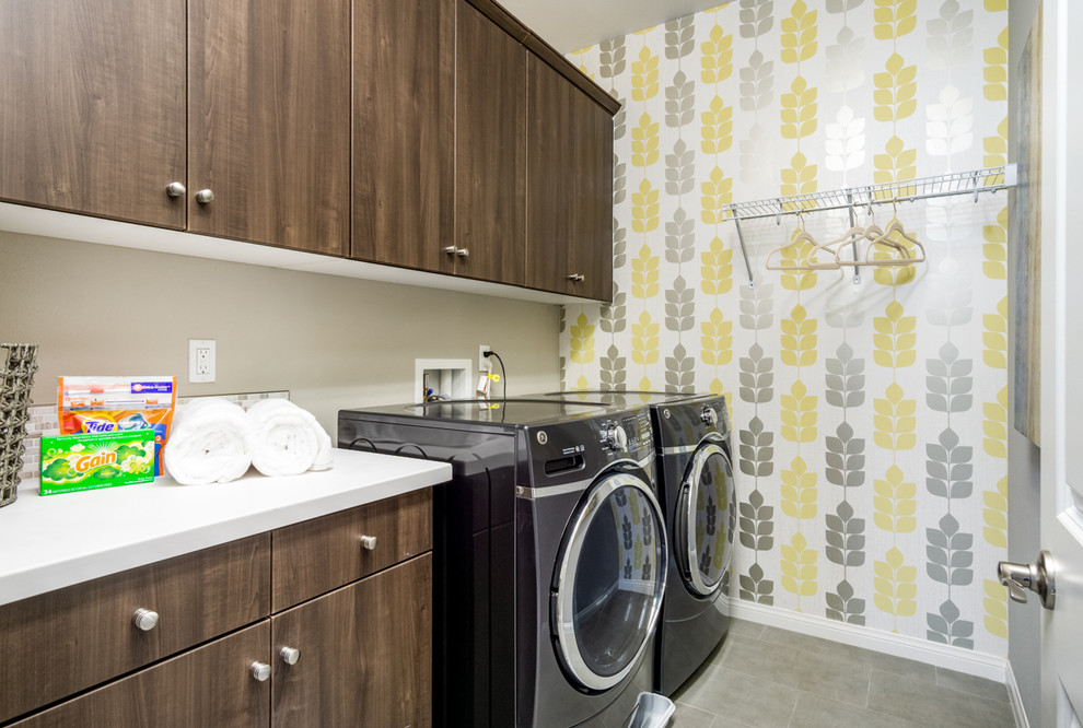 Imagen de lavadero lineal actual con armarios con paneles lisos, puertas de armario de madera en tonos medios, paredes multicolor, suelo gris y encimeras blancas