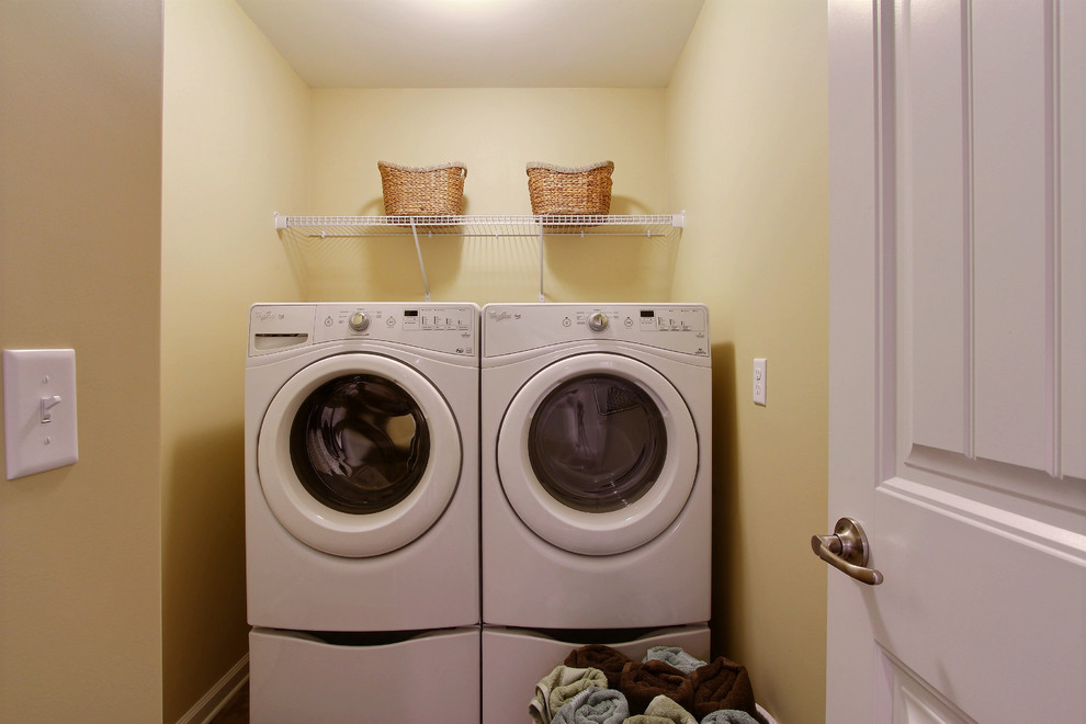 Idee per un piccolo ripostiglio-lavanderia classico con pavimento in laminato, lavatrice e asciugatrice affiancate, nessun'anta e pareti gialle
