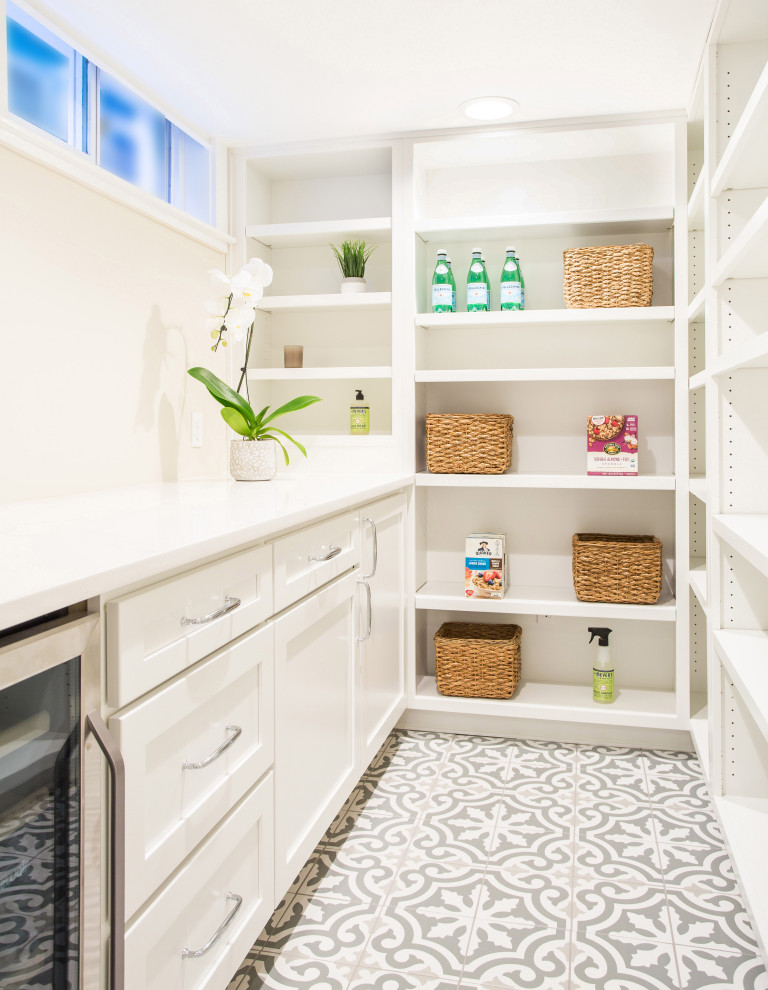 Dedicated laundry room - mid-sized farmhouse porcelain tile and gray floor dedicated laundry room idea in Seattle with a farmhouse sink, shaker cabinets, white cabinets, quartz countertops, white walls, a stacked washer/dryer and white countertops