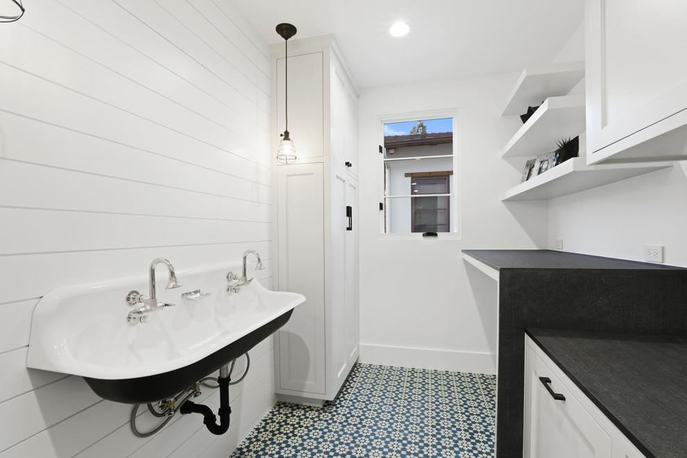 Idee per una piccola sala lavanderia minimalista con lavatoio, pareti bianche, pavimento in cemento, lavatrice e asciugatrice affiancate, pavimento blu, ante con riquadro incassato e ante bianche