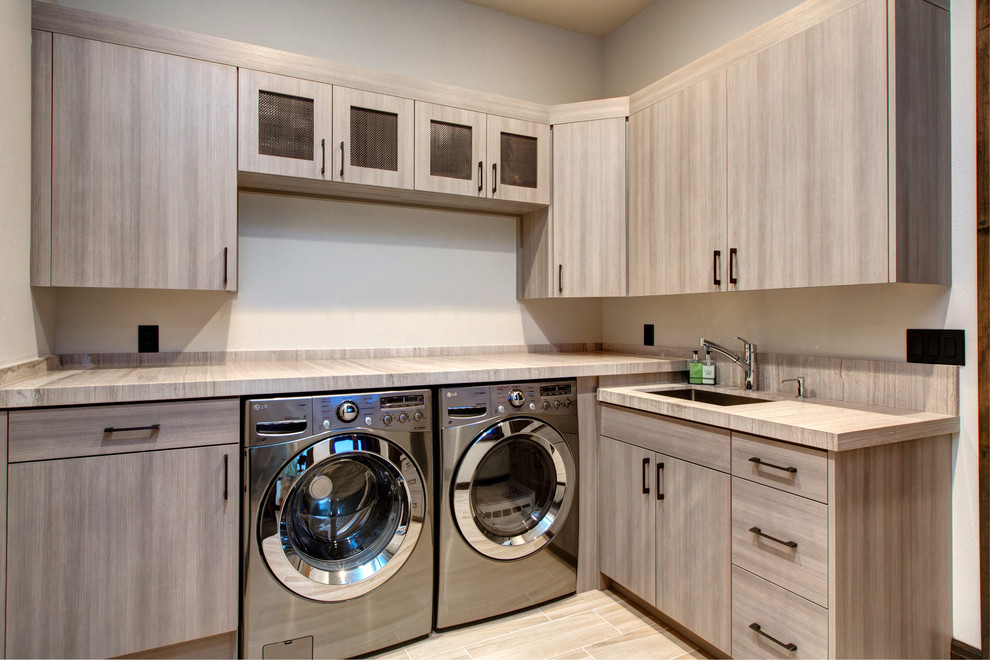Exempel på en stor rustik l-formad tvättstuga enbart för tvätt, med släta luckor, marmorbänkskiva, vita väggar, klinkergolv i porslin, en tvättmaskin och torktumlare bredvid varandra, grå skåp och en undermonterad diskho