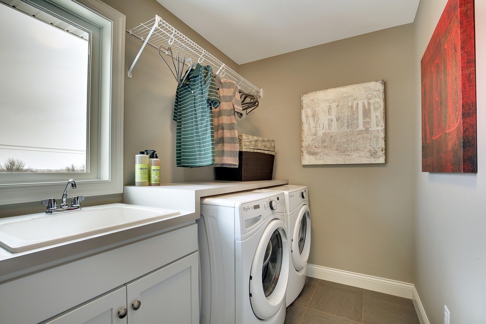 Large transitional single-wall dedicated laundry room photo in Minneapolis with a drop-in sink, recessed-panel cabinets, white cabinets, laminate countertops, gray walls and a side-by-side washer/dryer
