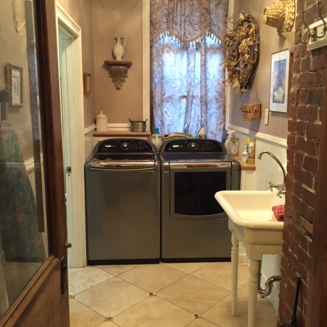 インディアナポリスにある高級な中くらいなヴィクトリアン調のおしゃれな洗濯室 (L型、エプロンフロントシンク、ベージュの壁、トラバーチンの床、左右配置の洗濯機・乾燥機) の写真