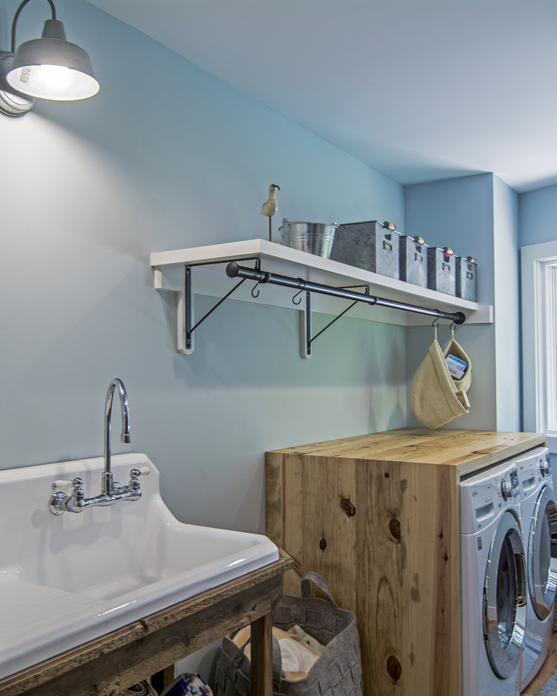 Idee per una grande lavanderia multiuso classica con lavello stile country, top in legno, pareti blu, parquet chiaro, lavatrice e asciugatrice affiancate e pavimento marrone