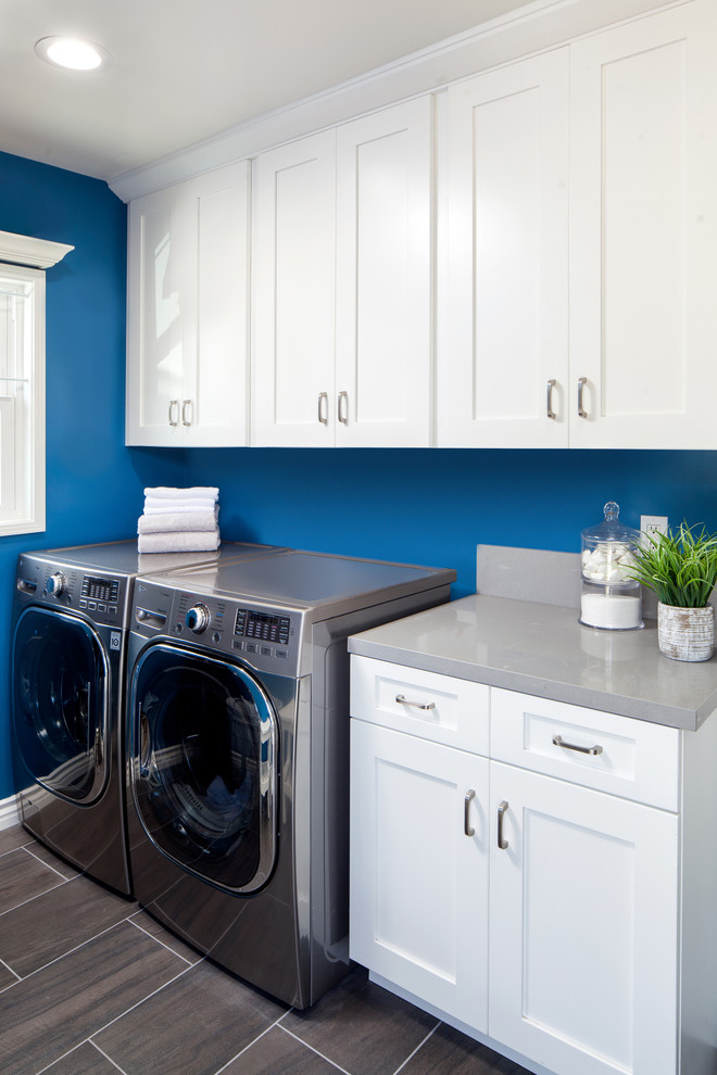 Idéer för små vintage parallella tvättstugor enbart för tvätt, med skåp i shakerstil, vita skåp, bänkskiva i kvarts, blå väggar, klinkergolv i porslin, en tvättmaskin och torktumlare bredvid varandra och grått golv