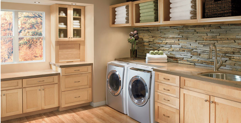 Example of a mid-sized l-shaped light wood floor dedicated laundry room design in Los Angeles with a drop-in sink, shaker cabinets, light wood cabinets, solid surface countertops, beige walls and a side-by-side washer/dryer