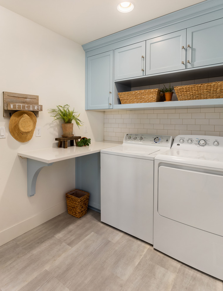 Zweizeilige, Kleine Moderne Waschküche mit Schrankfronten im Shaker-Stil, blauen Schränken, Mineralwerkstoff-Arbeitsplatte, weißer Wandfarbe, Porzellan-Bodenfliesen, Waschmaschine und Trockner nebeneinander, grauem Boden und weißer Arbeitsplatte in Portland