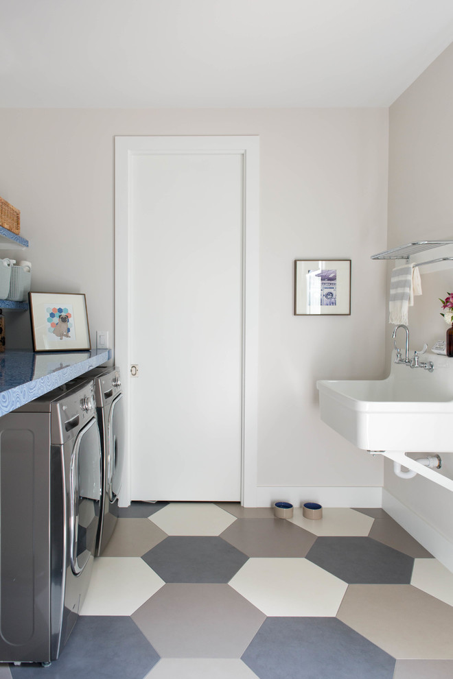 Zweizeilige Moderne Waschküche mit Ausgussbecken, beiger Wandfarbe, Waschmaschine und Trockner nebeneinander, buntem Boden und blauer Arbeitsplatte in Austin