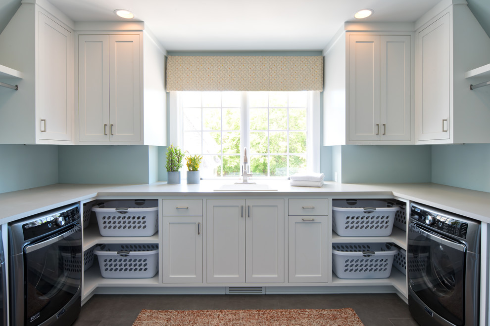 Exempel på en stor klassisk vita u-formad vitt tvättstuga enbart för tvätt, med en nedsänkt diskho, skåp i shakerstil, vita skåp, bänkskiva i onyx, blå väggar, en tvättmaskin och torktumlare bredvid varandra och grått golv