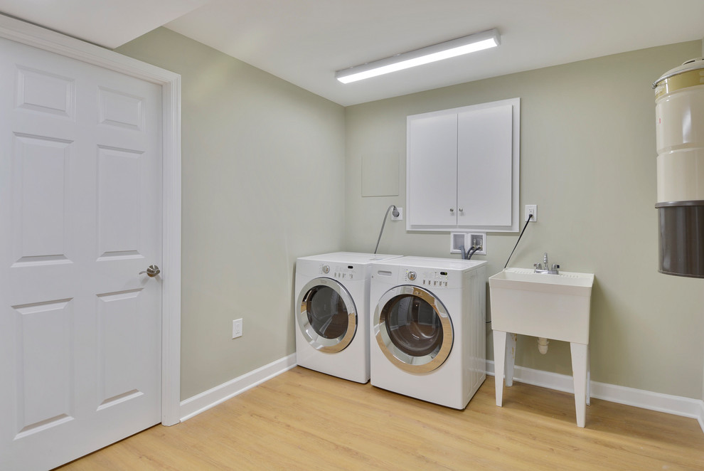ワシントンD.C.にある中くらいなトランジショナルスタイルのおしゃれな家事室 (スロップシンク、緑の壁、ラミネートの床、左右配置の洗濯機・乾燥機) の写真