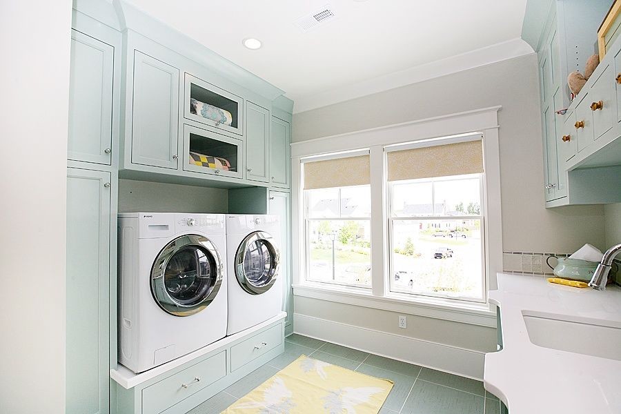 Diseño de cuarto de lavado de galera ecléctico con armarios con paneles empotrados, puertas de armario azules, paredes beige, suelo de baldosas de cerámica y lavadora y secadora juntas