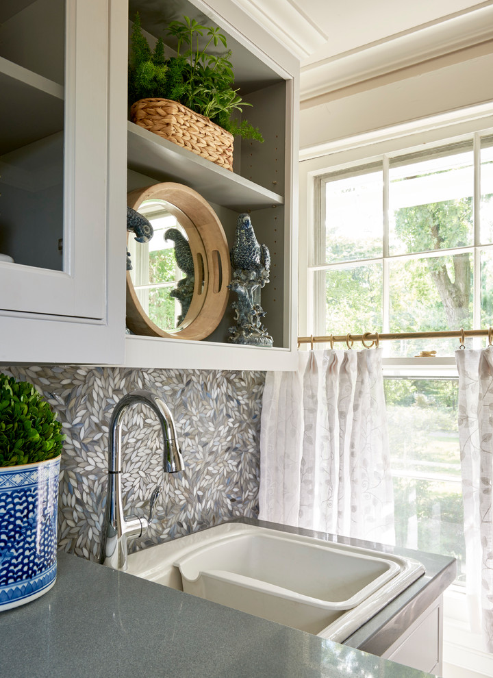 Inspiration for a large classic l-shaped separated utility room in New York with an utility sink, open cabinets, white cabinets, composite countertops, a side by side washer and dryer, beige walls and travertine flooring.