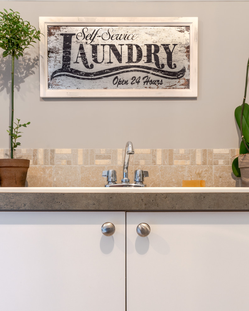 Idéer för att renovera en liten vintage grå l-formad grått tvättstuga enbart för tvätt, med en nedsänkt diskho, släta luckor, vita skåp, laminatbänkskiva, grå väggar, travertin golv, en tvättmaskin och torktumlare bredvid varandra och grått golv