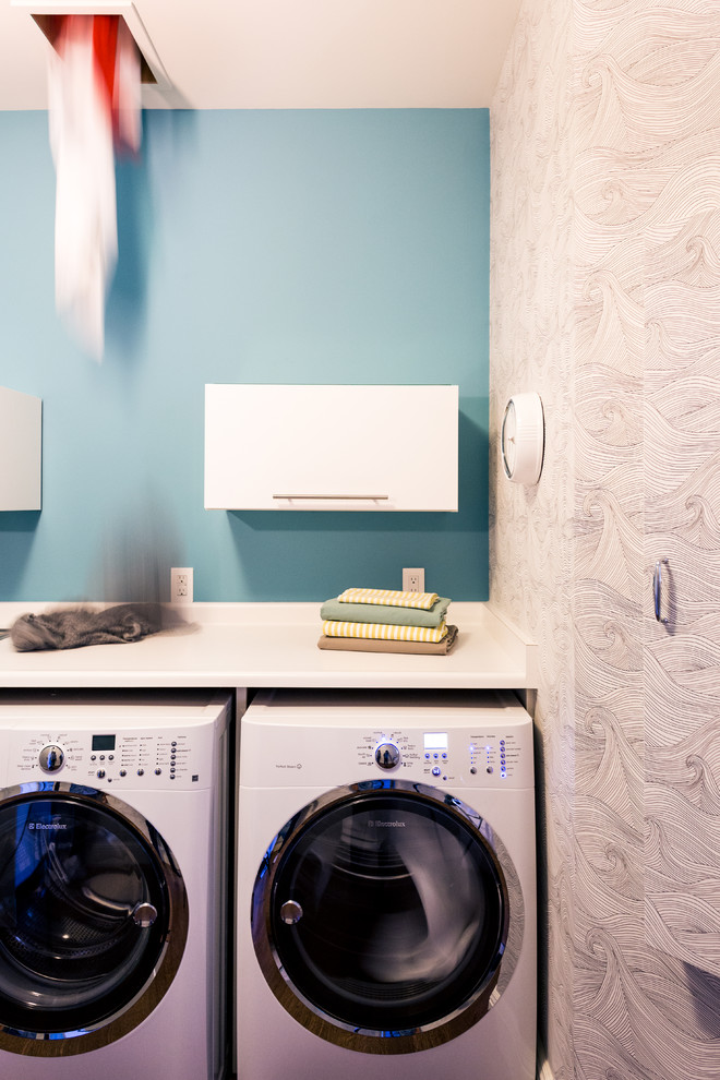 Bild på en funkis tvättstuga, med blå väggar och en tvättmaskin och torktumlare bredvid varandra