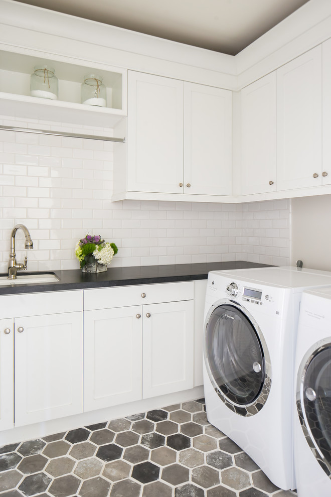 Elegant l-shaped multicolored floor dedicated laundry room photo in Orange County with an undermount sink, white cabinets, a side-by-side washer/dryer, black countertops, shaker cabinets and gray walls